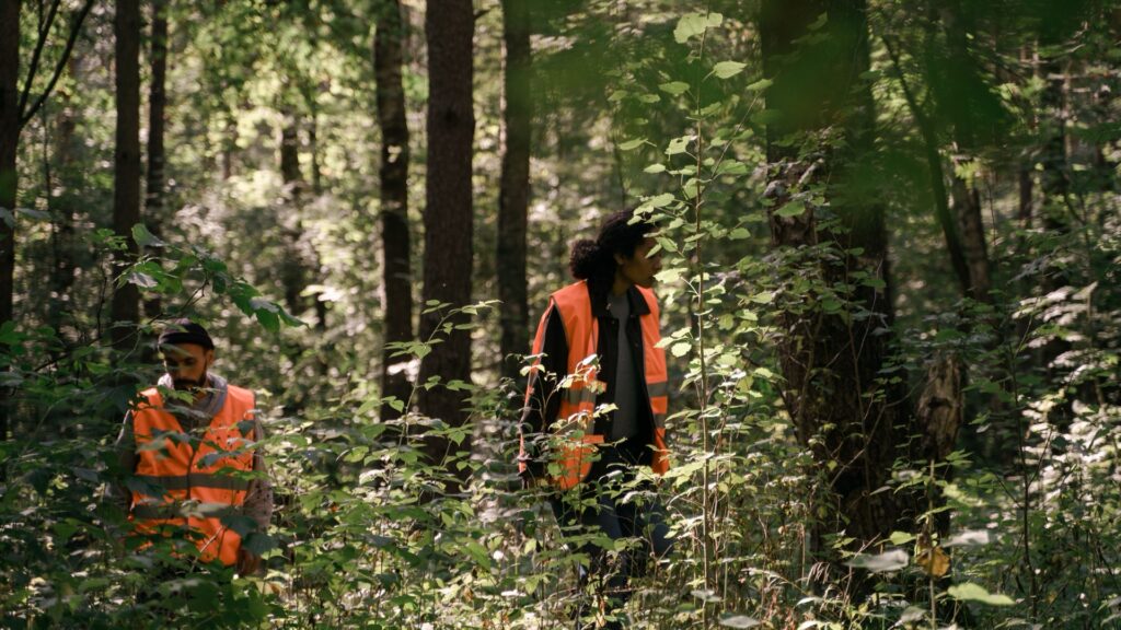 Naturschutzmitarbeiter, der schwarze Arbeitsstiefel trägt, im Wald