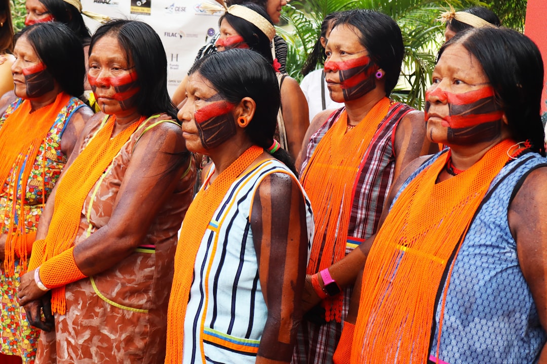 Indigenous women with painted faces and orange scarves.